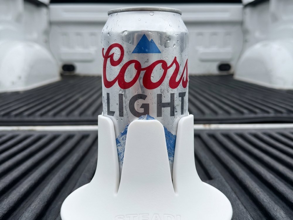 A can standing in a white Steadi on the open tailgate of a white pickup truck.